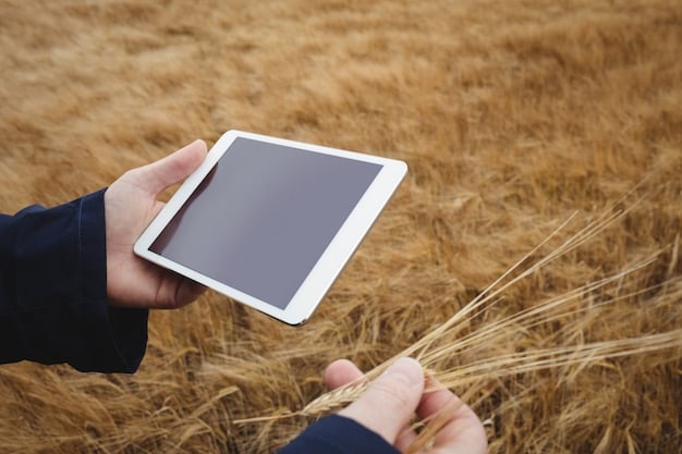 A close-up shot of a farmer using a tablet in a field. The tablet's screen shows a detailed map of the farm with color-coded zones indicating soil moisture levels, crop health, and other key data metrics, all powered by AI algorithms.