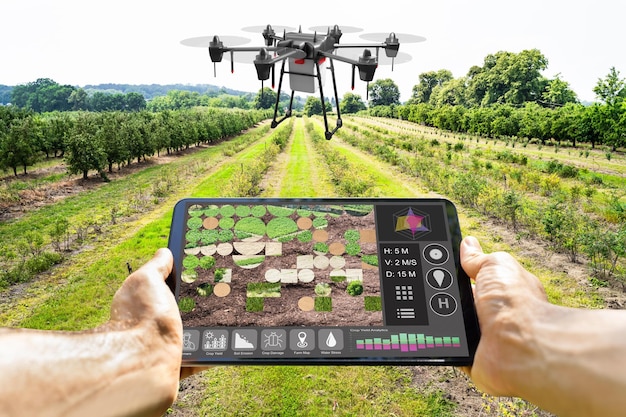 An agricultural drone equipped with specialized multispectral cameras is seen capturing images of a field while hovering. The field shows various subtle color differences indicating different crop health levels. A worker on the ground monitors the drone's progress using a tablet.