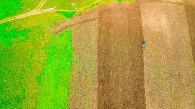 An aerial view of a farm implementing conservation tillage, showing the residue of previous crops left on the soil surface. The image should illustrate how this practice reduces soil erosion and sequesters carbon.