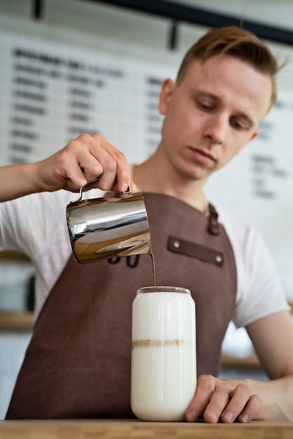 A visually appealing photograph of a coffee shop bar, showcasing a barista expertly frothing oat milk to create latte art on a cappuccino. The focus is on the creamy texture of the oat milk and the intricate latte art.