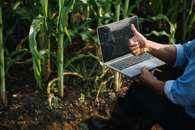 A close-up shot of a farmer analyzing data on a laptop in a barn. The screen displays agricultural software with charts and graphs showing crop yields and other relevant metrics.