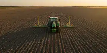 Modern tractor with GPS steering system precisely working a field at sunset, optimizing operations.